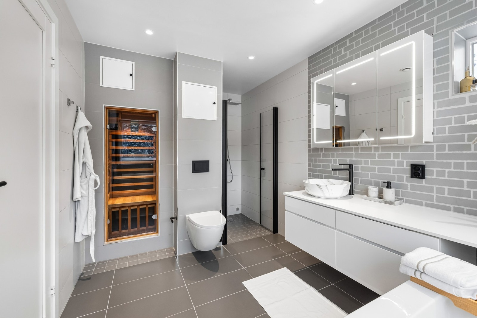 Downlights er installert, og badet har gulvvarme, vegghengt toalett og plassbygd infrarød badstue - et flott innslag i boligen. Galleribilde