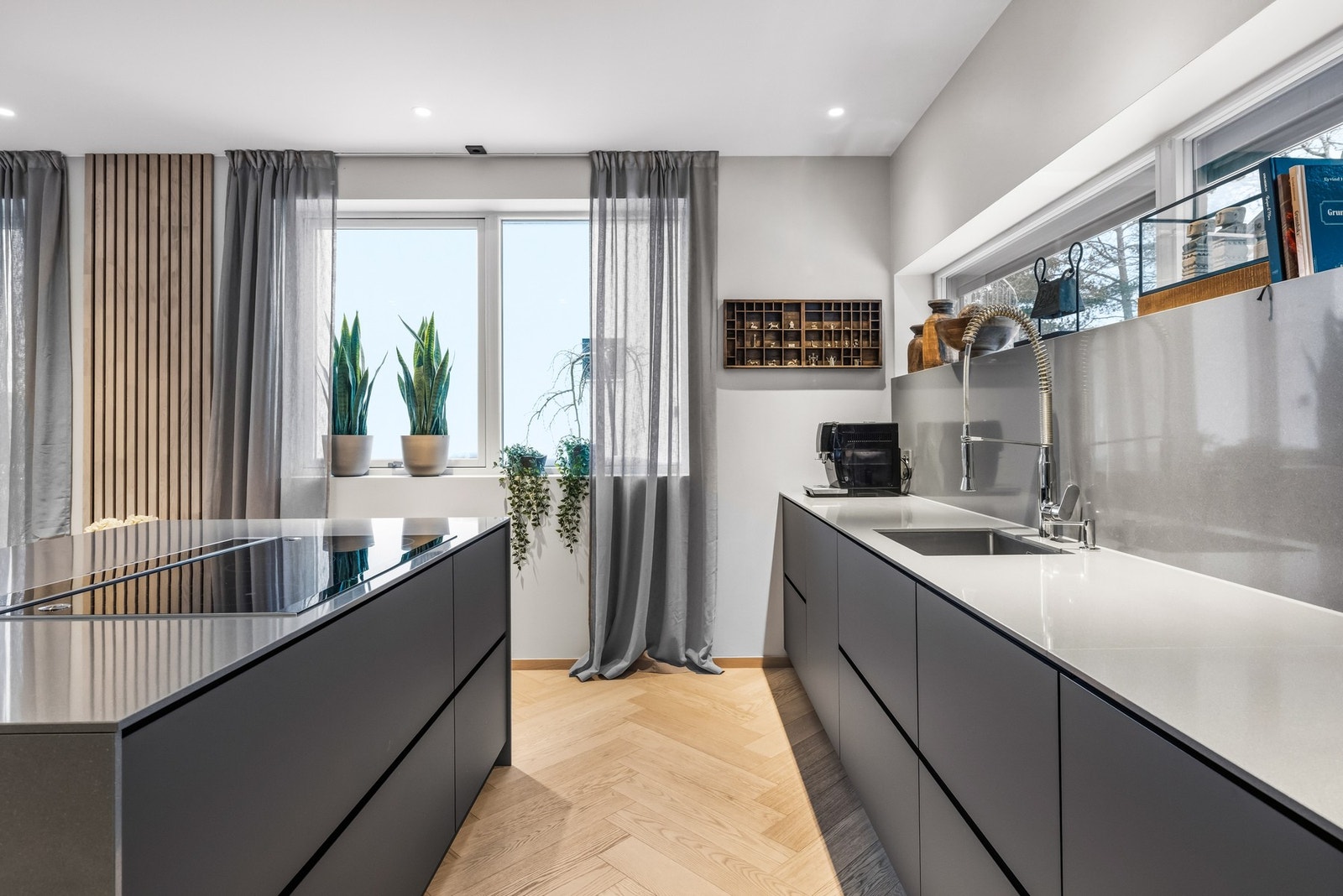 Innredningen har grå, glatte fronter, nedfelt oppvaskkum, integrert såpedispenser og benkeplate av kompositt. Galleribilde