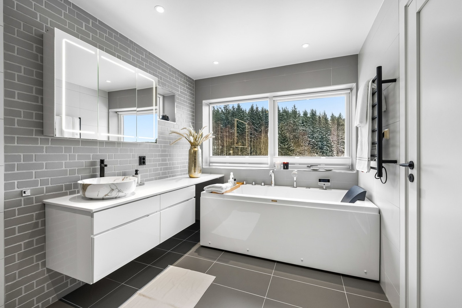 På badet er det både et dusjhjørne og et deilig badekar, der førstnevnte har stor regnfallsdusj og innfellbare glassdører. Det er også håndkletørker på to av badene. Galleribilde