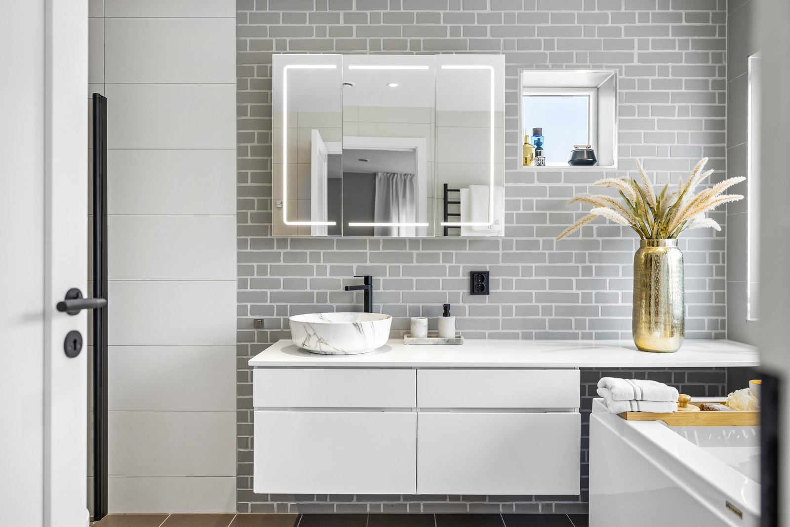 Badet tilknyttet hovedsoverommet er stilrent innredet med vegg- og gulvfliser i ulike gråtoner. Galleribilde