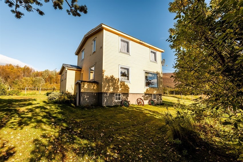 Eneboligen har hage med plen og busker.
