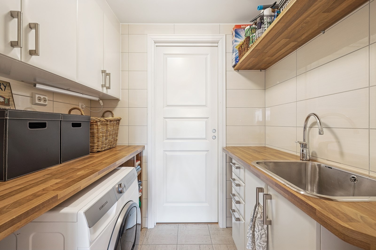 Vaskerom med bod i bakkant. Rommet har flislagt gulv med gulvvarme, fliser på vegg og malte flater i tak. Vaskerommet har benkeinnredning med nisje til vaskemaskin og tørketrommel, veggskap, plassbygde hyller utslagsvask samt opplegg for vaskemaskin. Galleribilde