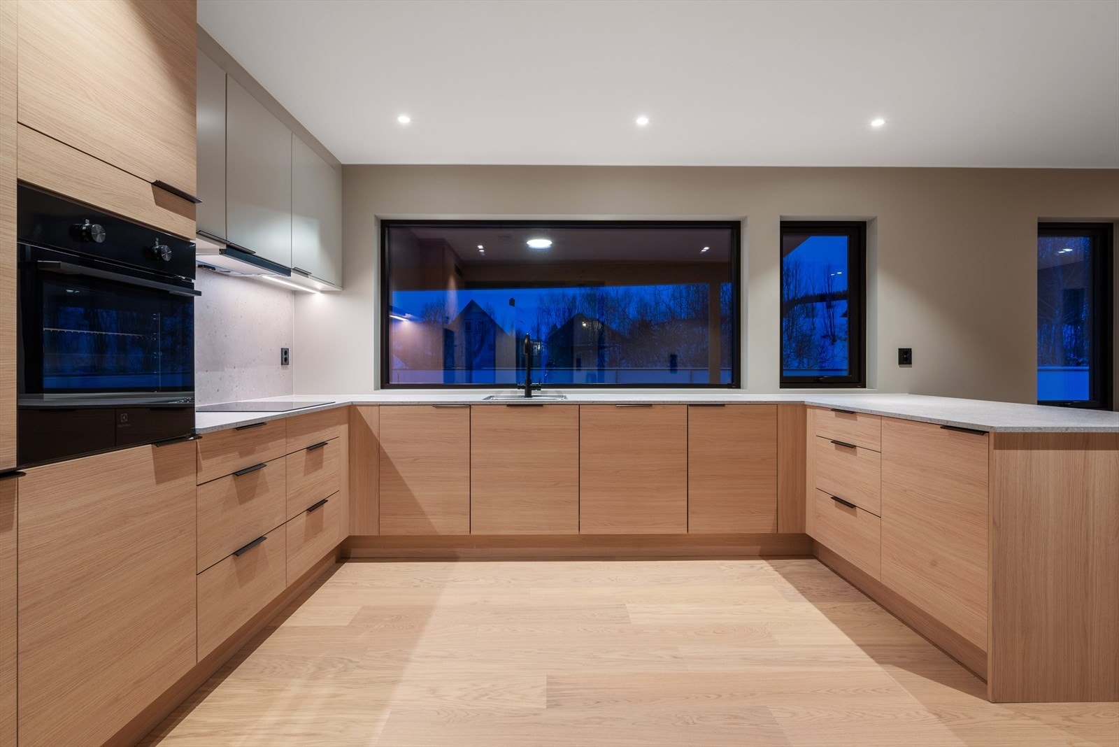 Kjøkkeninnredning med glatte fronter og integrerte hvitevarer. Mekanisk avtrekksvifte over stekesonen Galleribilde