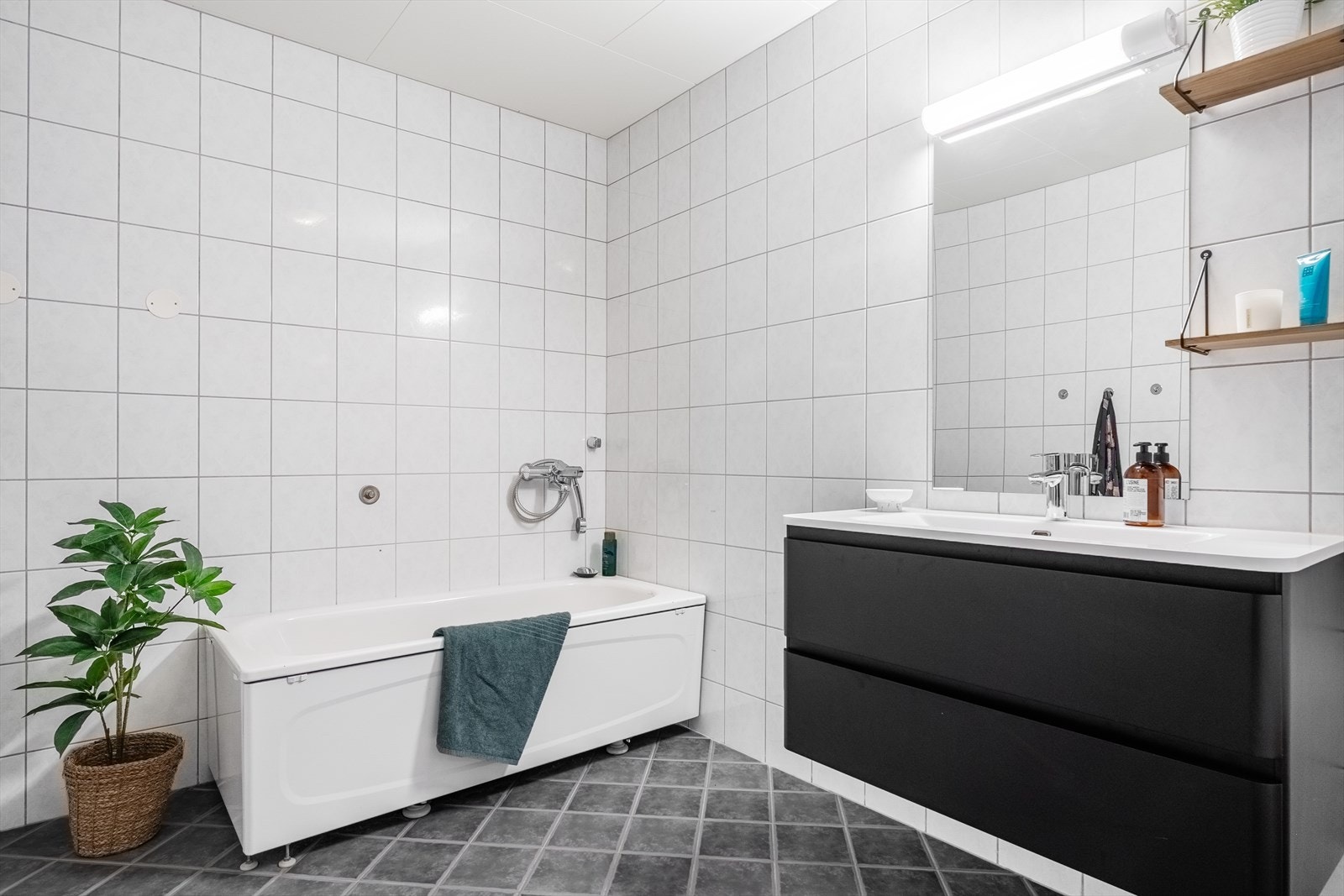 Rommet er innredet med servant i møbel, speil, toalett og badekar. Galleribilde