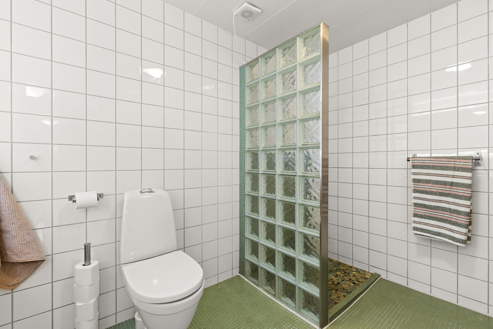 Badet har dusjhjørne med glassbyggersten og dekorfliser på gulv Galleribilde