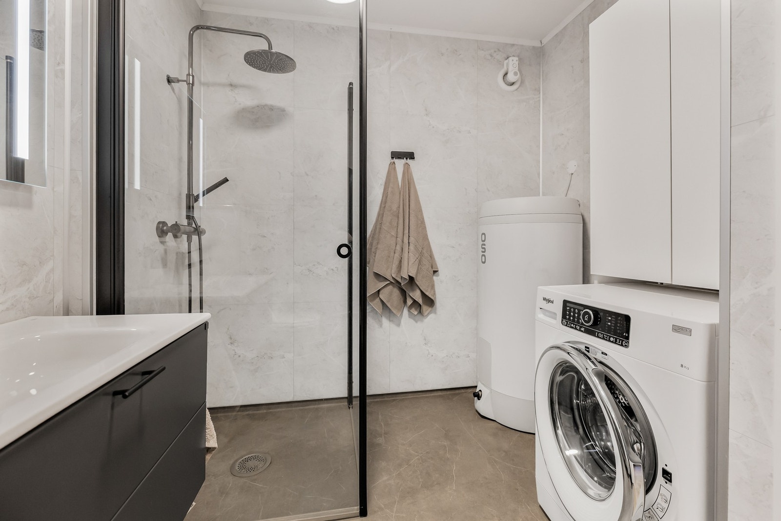 Baderommet har vegghengt servantinnredning, speil med sidelys, gulvstående høyskap, dusjhjørne og vegghengt toalett. Galleribilde