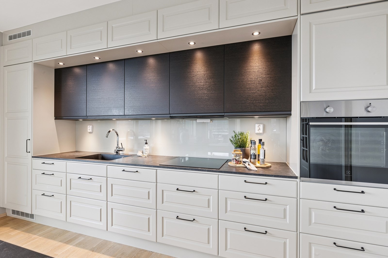 Overskapene i midten har sorte fronter som skaper en elegant kontrast og gir kjøkkenet et eksklusivt uttrykk. Galleribilde