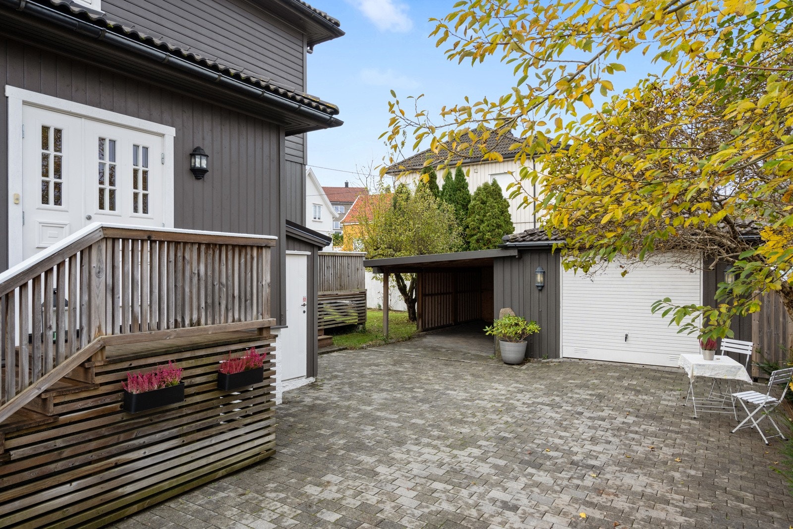 Pent opparbeidet og steinlagt gårdsplass med garasje og carport. Galleribilde