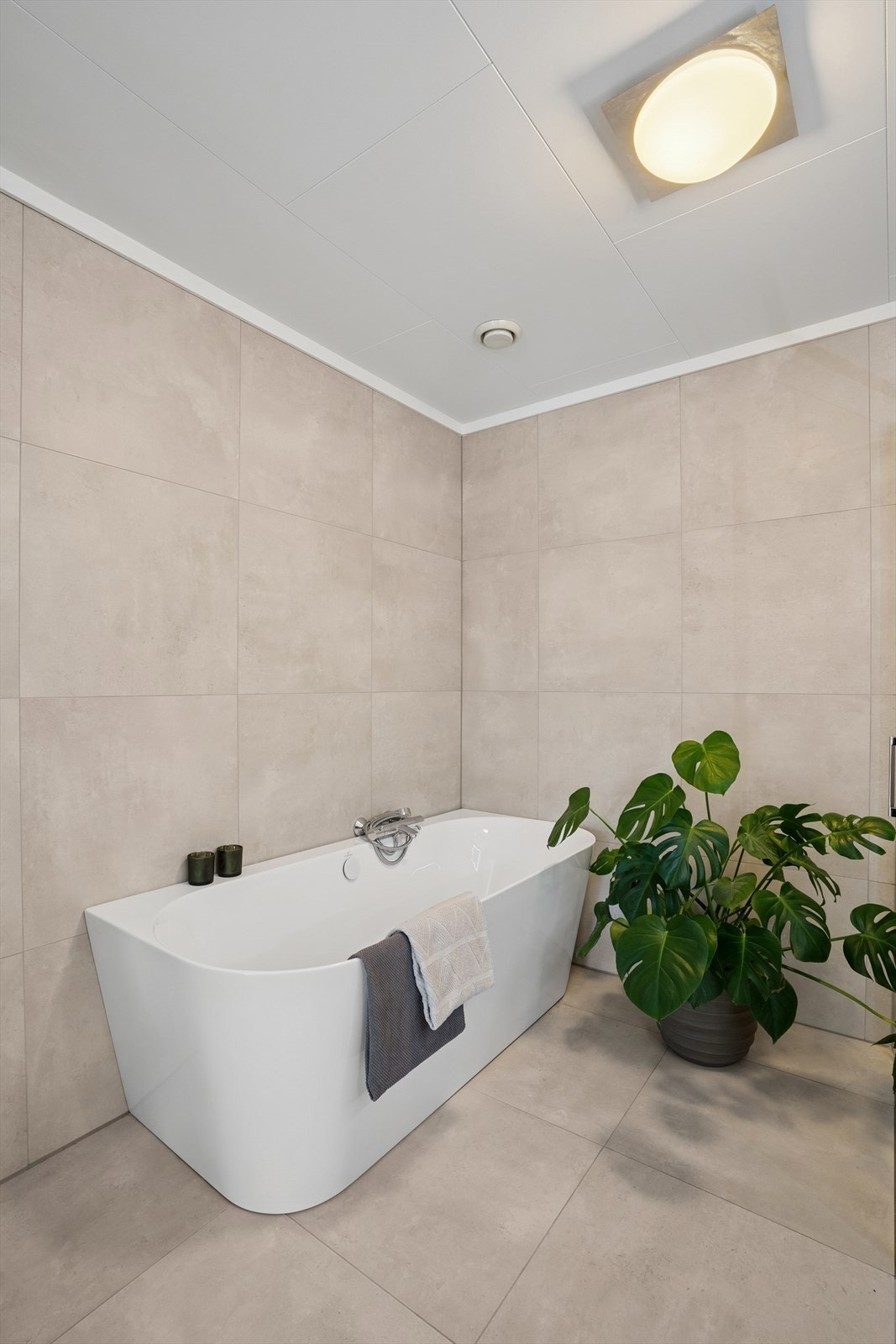 Her finner du et nedsenket dusjhjørne, frittstående badekar og en pen, stor servant med skuffer som gir god oppbevaringsplass Galleribilde