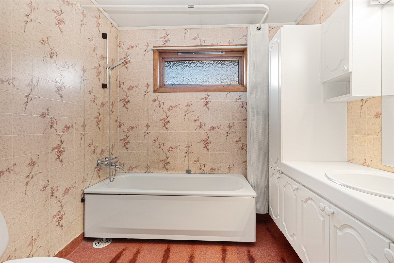 Badet er av eldre dato, med belegg på gulv med varmekabler. Badet inneholder en meget romslig baderomsinnredning med nedfelt servant og speil med overlys. Badet er også innredet med badekar og toalett. Galleribilde