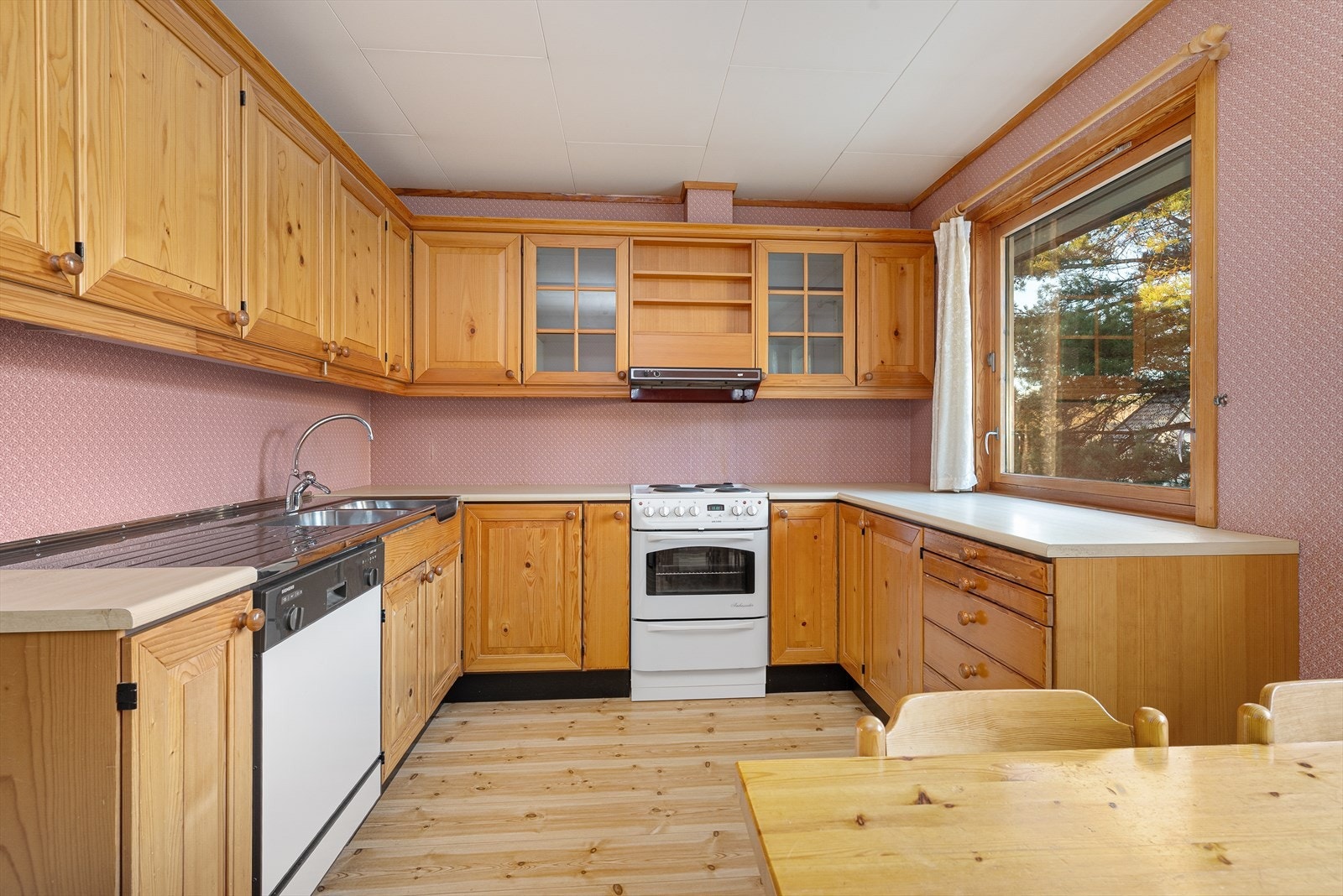 Eldre kjøkkeninnredning med god oppbevaringsplass. Det er også gode arbeidsflater på laminert benkeplate, hvor det tilføres godt arbeidslys fra vinduet. Galleribilde