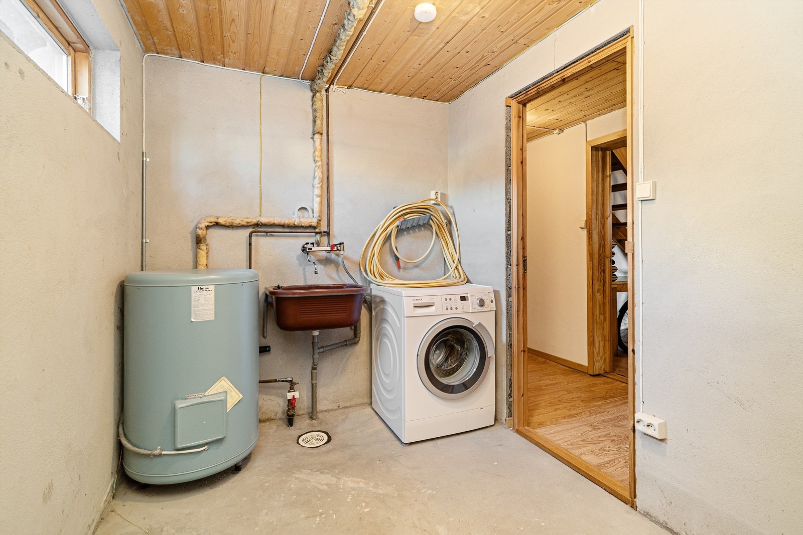Det er eget vaskerom i kjelleretasjen, med betonggulv, vegger i puss og tak med panel. Vaskerommet har utslagsvask og opplegg for vaskemaskin. Varmtvannstanken er også plassert her. Galleribilde