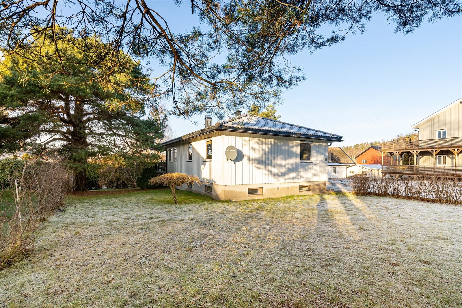 Boligen ligger på en relativt flat tomt som er pent opparbeidet med gruset gårdsplass og hage med plenarealer, trær og prydbusker. Galleribilde