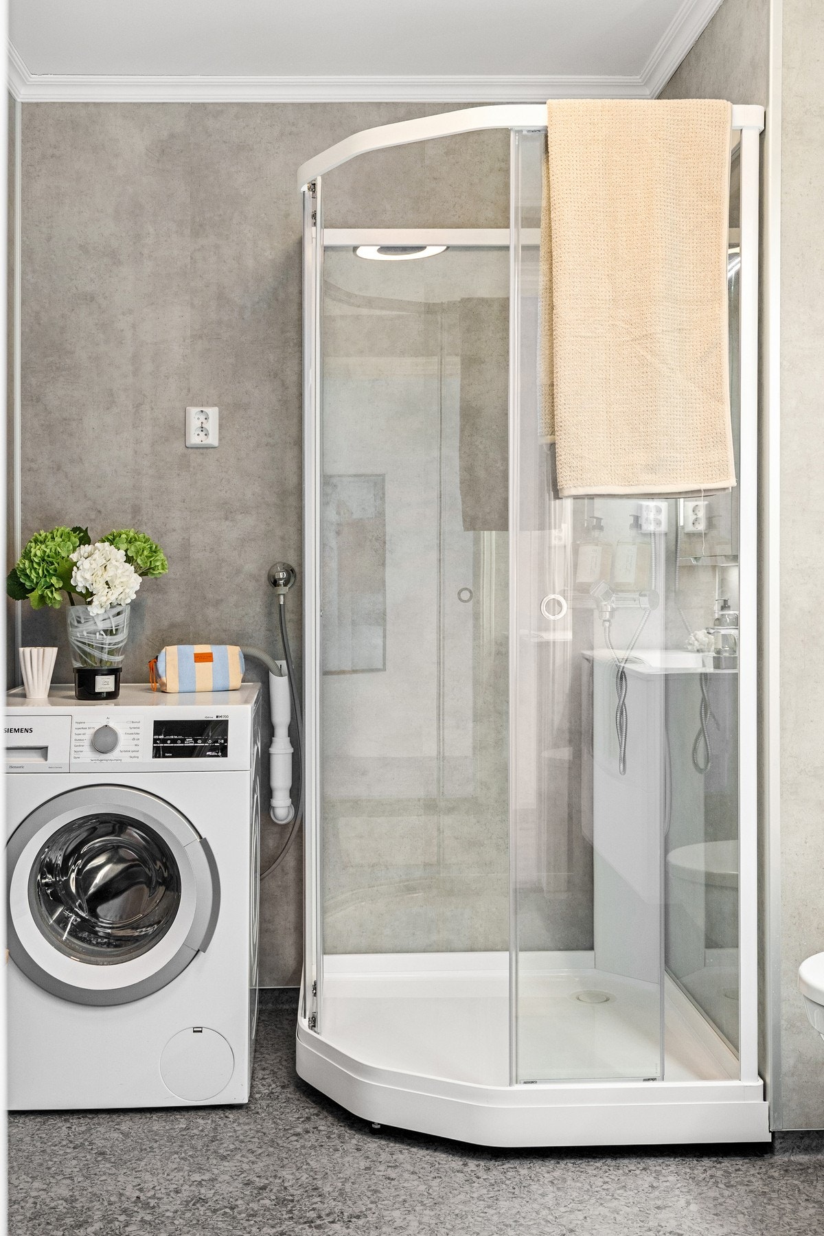 Det har vinylbelegg på gulv med elektrisk gulvvarme, baderomsplater på vegger, dusjkabinett, vegghengt toalett med innebygget sisterne og servant med skuffeinnredning. Galleribilde