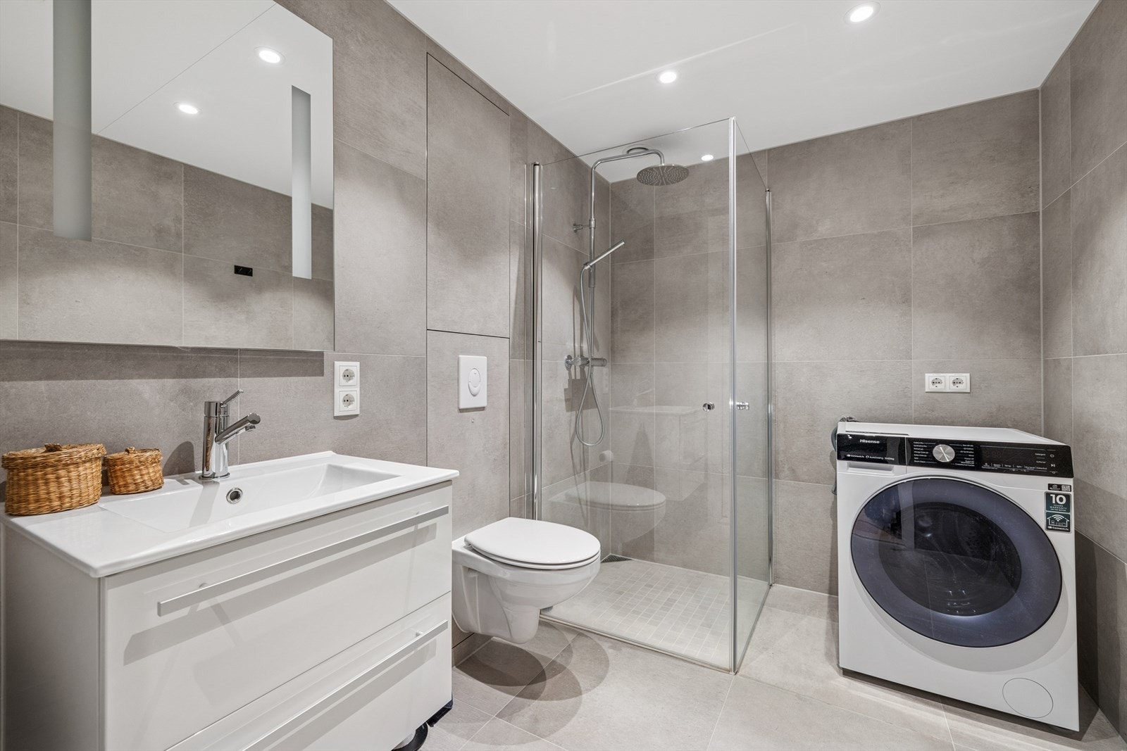 Dusjhjørne med regndusjarmatur og hånddusj, vegghengt wc og opplegg for vaskemaskin. Galleribilde