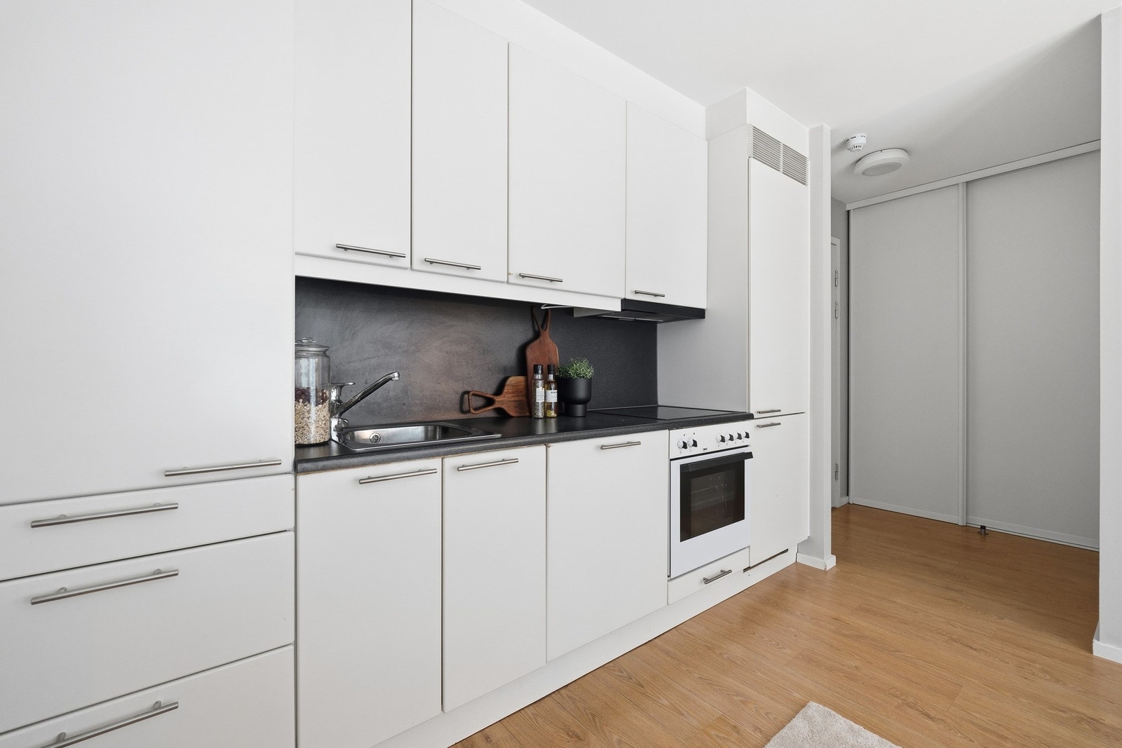 Praktisk kjøkkeninnredning med rene linjer og slitesterk laminat benkeplate. Galleribilde