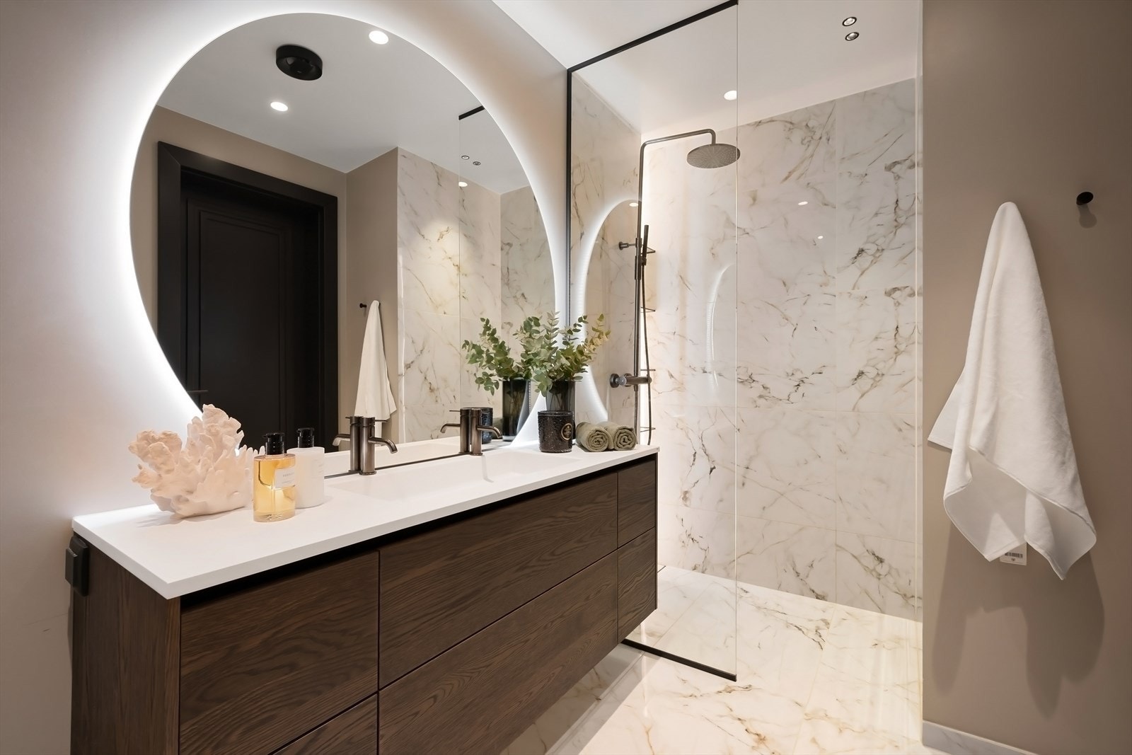 Lekkert bad med eksklusive fliser, armaturer og spesialtilpasset LED-belysning i spesiallagde hyller i dusjen og glassvegg. Galleribilde