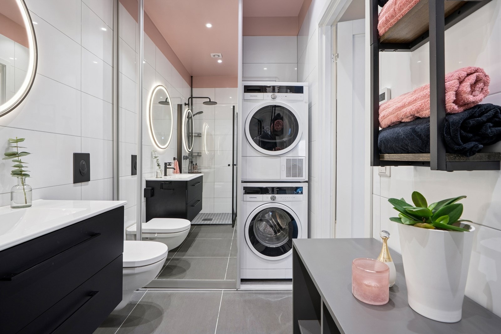 Badet har også opplegg for vaskemaskin og tørketrommel, diskret plassert bak en praktisk skyvedør med speil Galleribilde