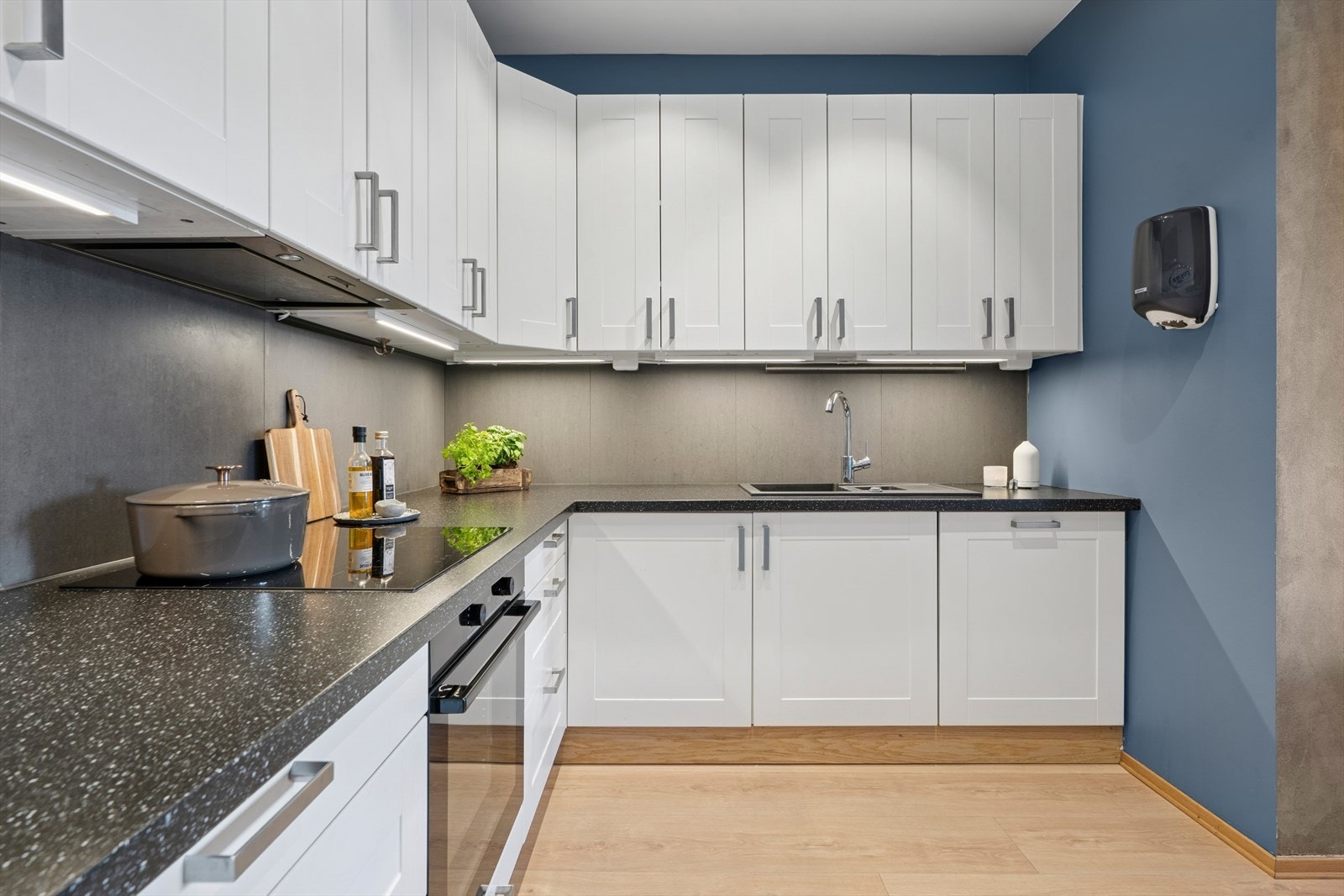 Innredningen har hvite, profilerte fronter, laminat benkeplate og en nedfelt oppvaskkum i sort kompositt med ettgreps blandebatteri Galleribilde