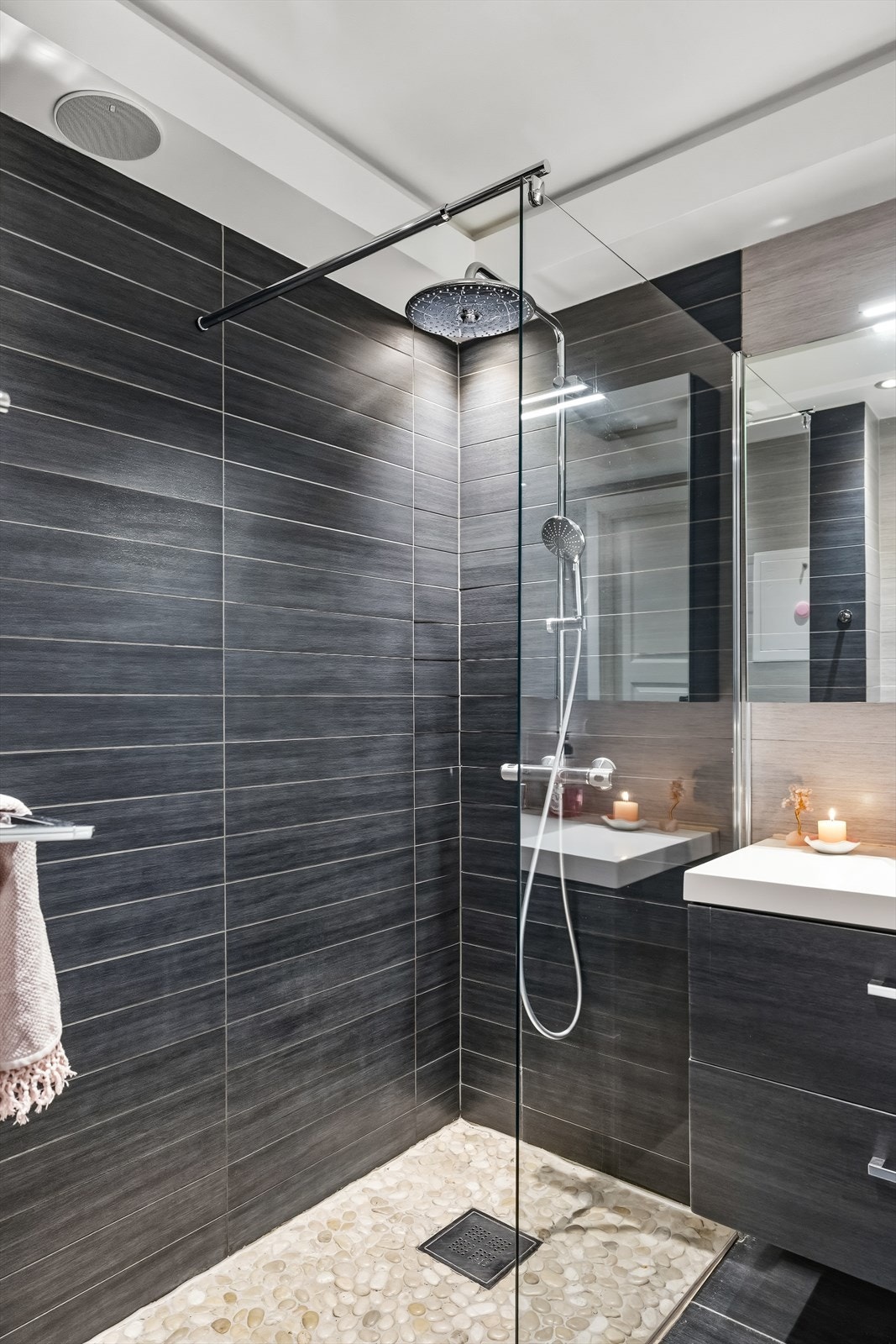 Stor dusjnisje med rullestensgulv og regnfallsdusj, og praktisk opplegg for håndklær. Galleribilde