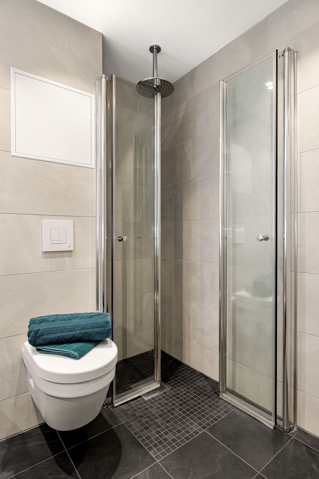 Badet er for øvrig utstyrt med dusjhjørne med innfellbare dører og takmontert regnfallsdusj, veggmontert toalett og opplegg for vaskemaskin. Galleribilde