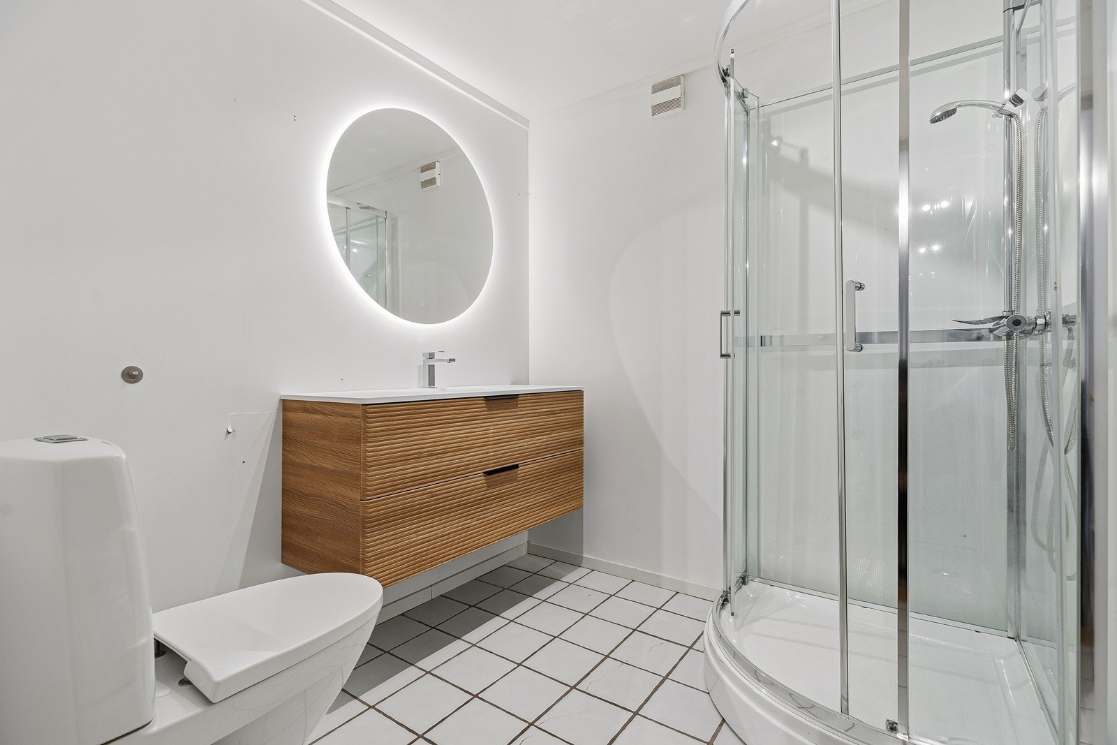 Pent baderom bestående av toalett, baderomsinnredning og dusjkabinett Galleribilde