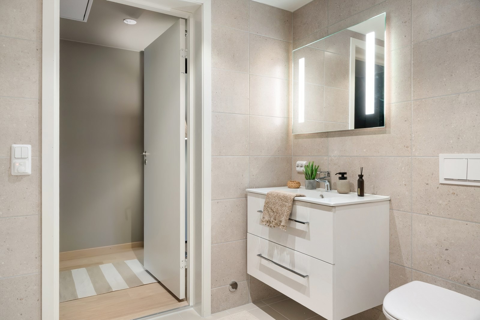 Badet er innredet med vegghengt toalett, vask i seksjon, speil med belysning og dusjhjørne. Det er opplegg for vaskemaskin. Galleribilde