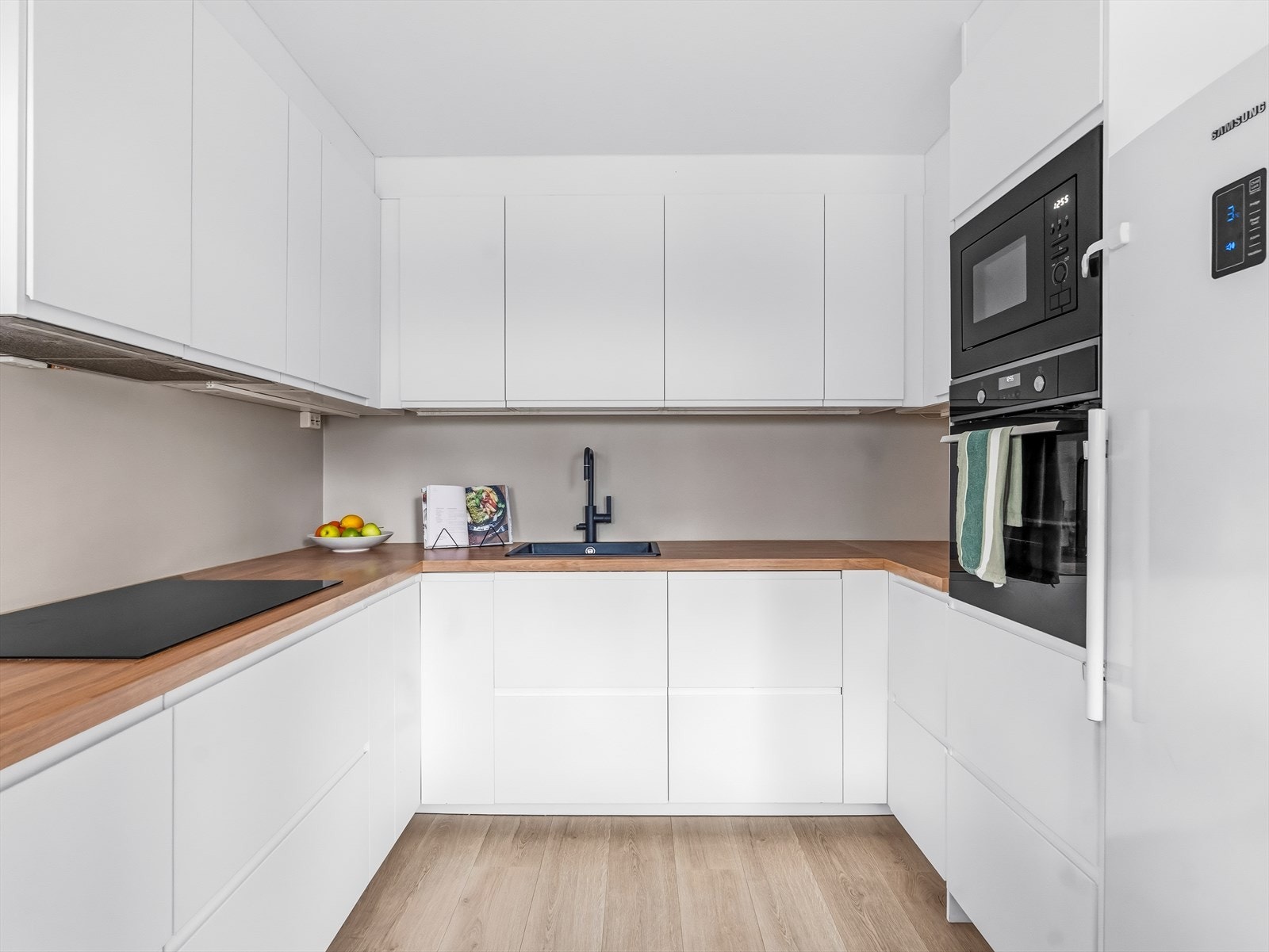 Det er plass til frittstående kjøle-/fryseskap. Videre er det montert belysning under overskapene. Galleribilde