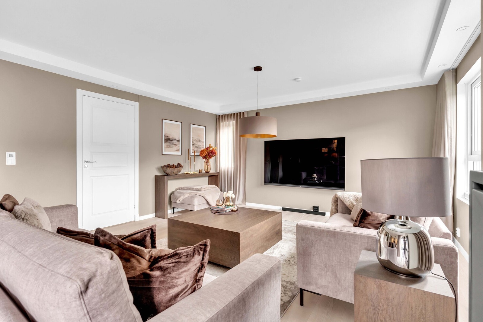 Boligen åpner seg med en romslig stue hvor store vindusflater slipper inn rikelig med dagslys. Her er det lagt parkett på gulvene og vegger malt i lyse fargetoner, som skaper en tidløs og behagelig atmosfære. Galleribilde