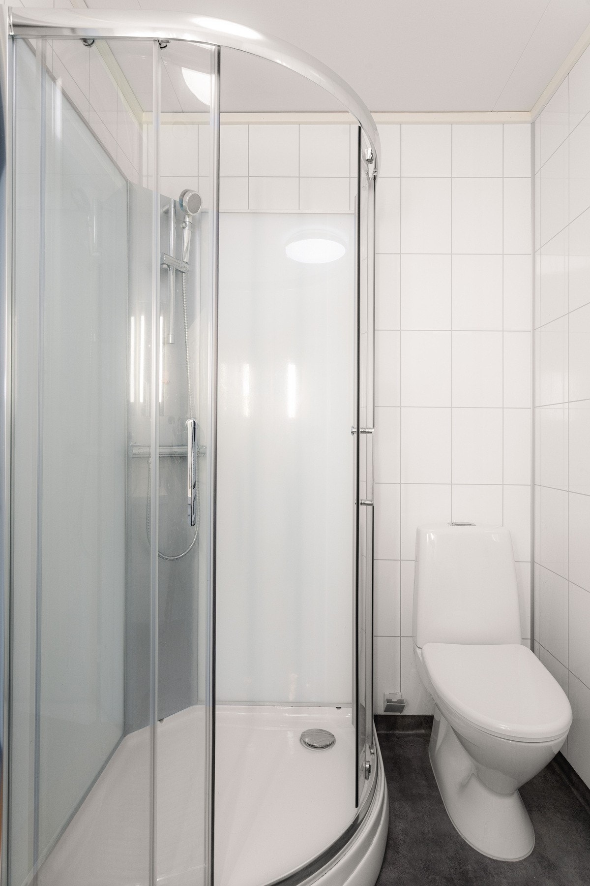 Videre er badet utstyrt med dusjkabinett, gulvstående toalett og opplegg for vaskemaskin. Galleribilde