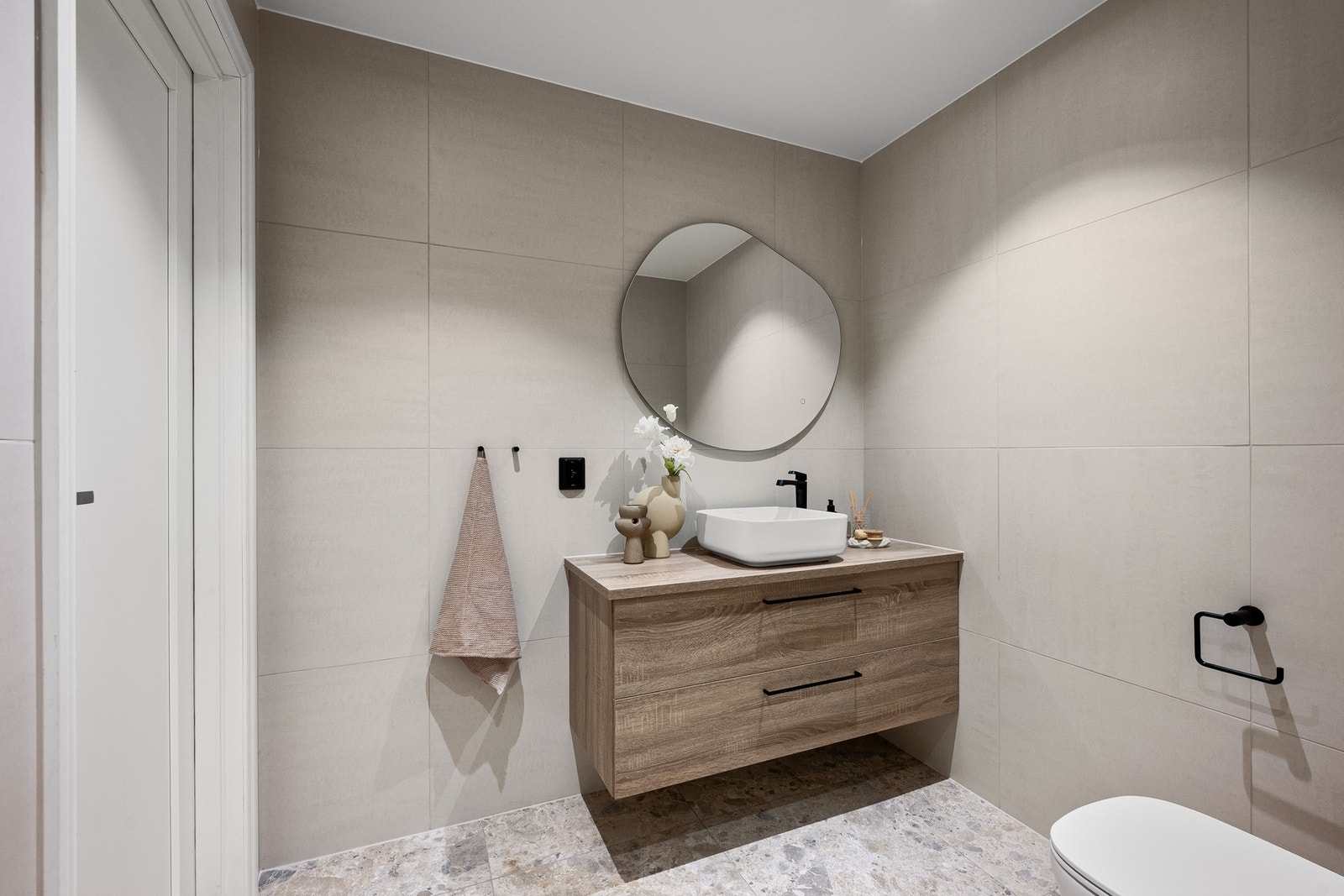 Servantskap med glatte fronter og ovenpåliggende servant, speil med integrert belysning og vegghengt toalett gir et ryddig og moderne preg. Galleribilde