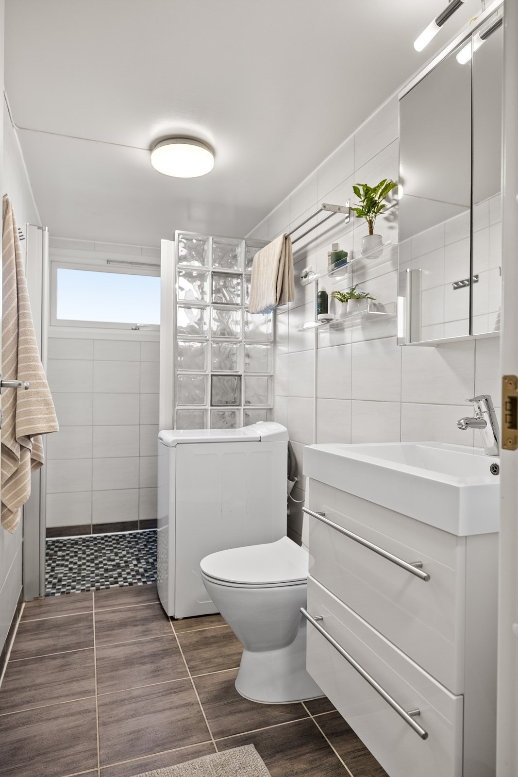 Innredningen fremstår med normal bruksslitasje, samtidig som rommet gir et ryddig og velholdt helhetsinntrykk. Veggene er flislagt og gir et tidløst, slitesterkt og lettstelt uttrykk, mens det malte taket bidrar til en lys og luftig romfølelse. Galleribilde