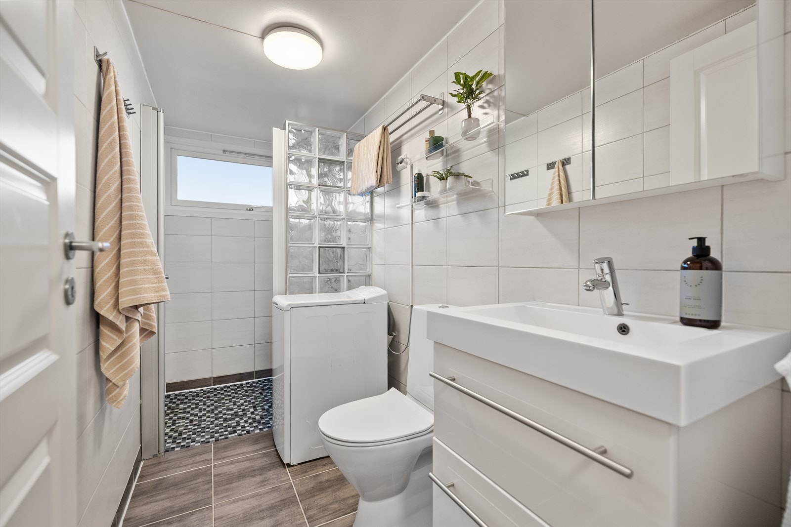 Baderommet fremstår som både funksjonelt og pent, med flislagt gulv utstyrt med varmekabler som gir behagelig komfort året rundt. Galleribilde