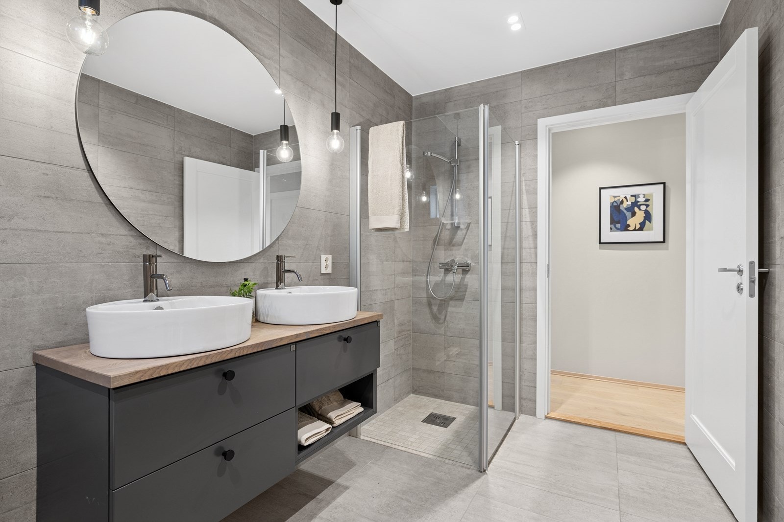 Badet er utstyrt med vegghengt toalett, dusjhjørne med glassvegger, frittstående badekar, samt baderomsinnredning med to servanter. Galleribilde