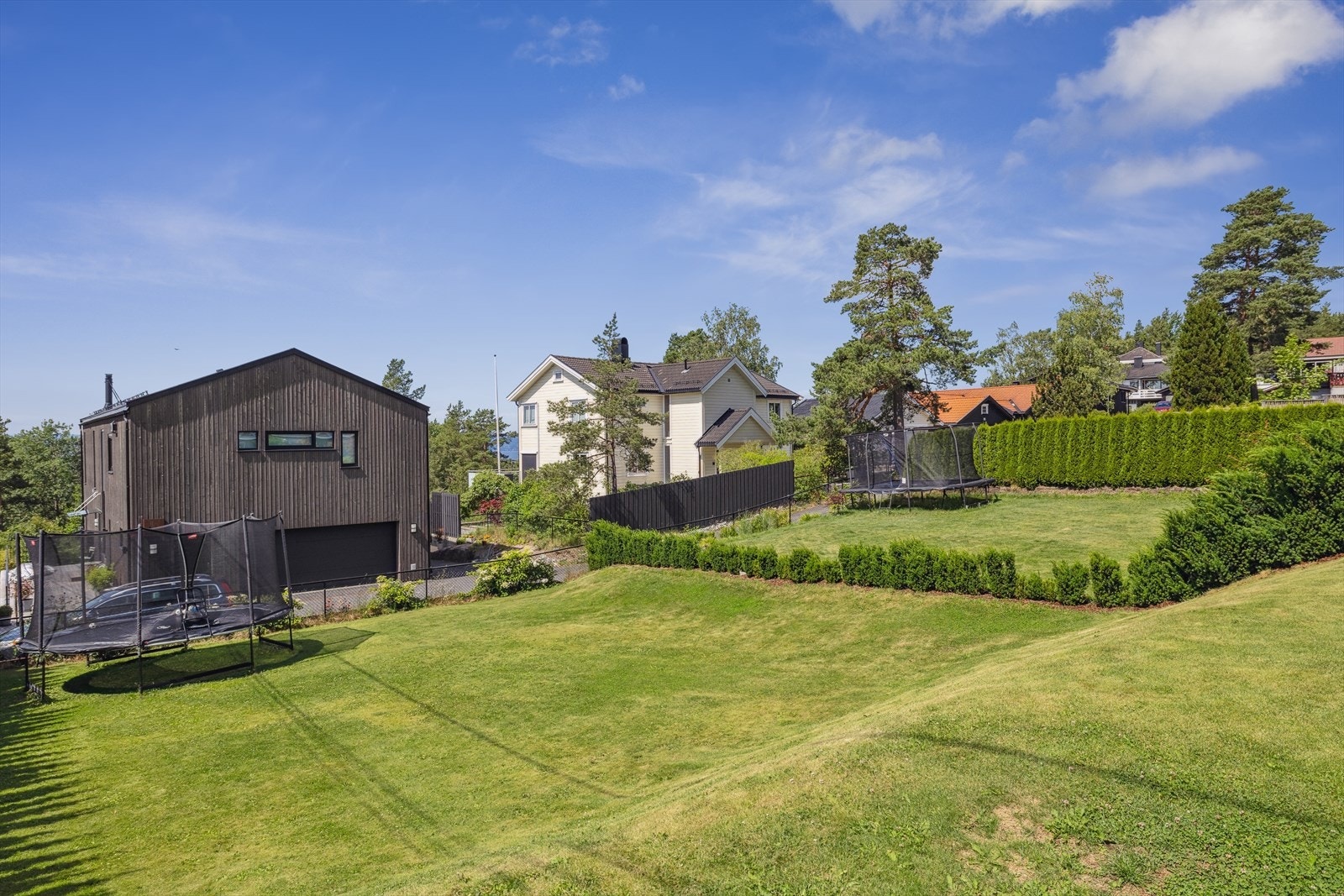 Lettstelt hage som er opparbeidet med store plenarealer, hekk og diverse beplantning. Galleribilde