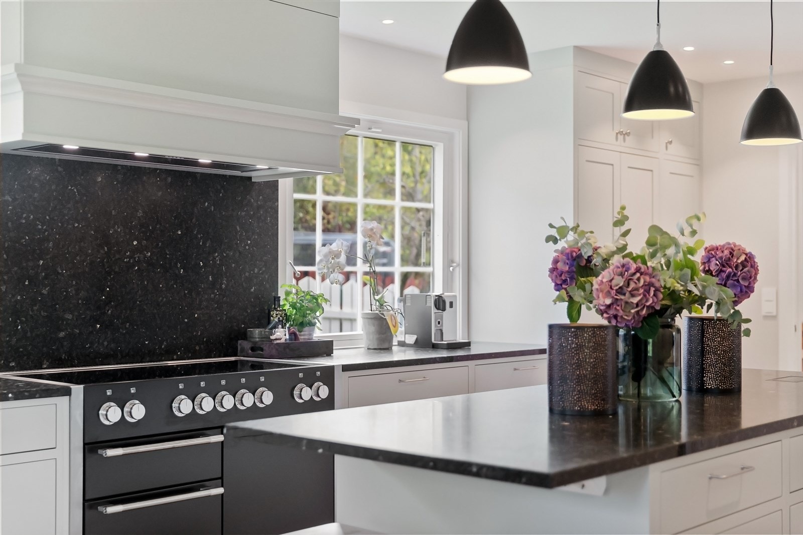 Frittstående kjøkkenøy med plass til barstoler under benk. Benkeplatene er i Larvikitt Galleribilde