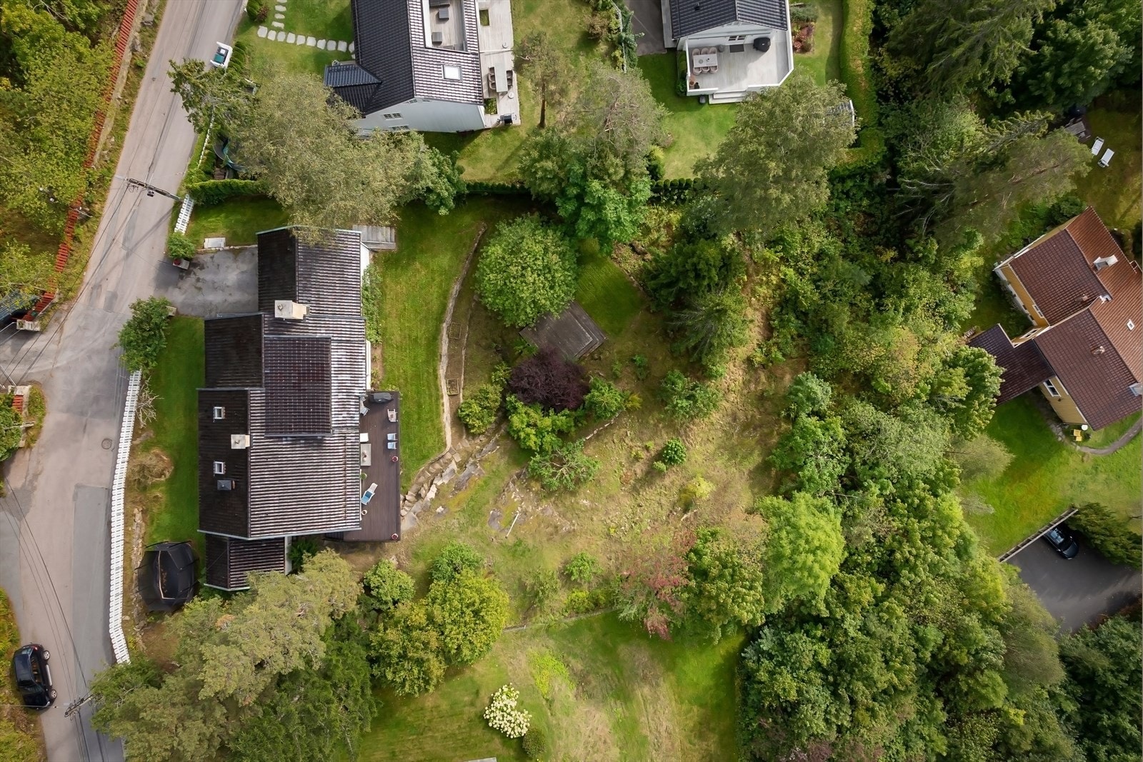 Pent opparbeidet tomt over flere nivåer med bl.a. gressplen, vakre steinmurer og flaggstang Galleribilde