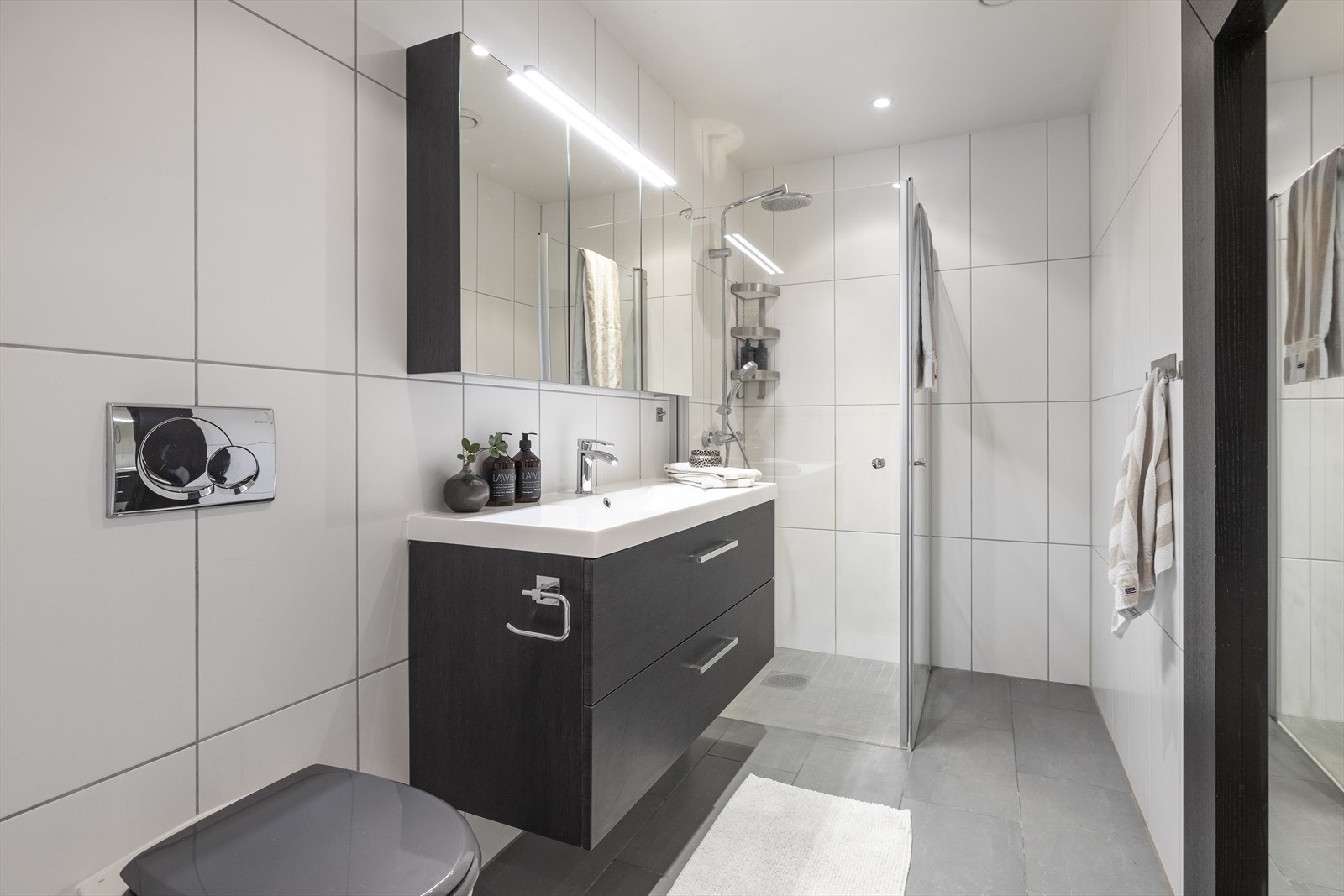 Bad 1.etasje utstyrt med baderomsinnredning med servant, speil, lys, dusjhjørne med glassdører og vegghengt toalett. Baderomsinnredning, servant og blandebatteri byttet i 2019 Galleribilde