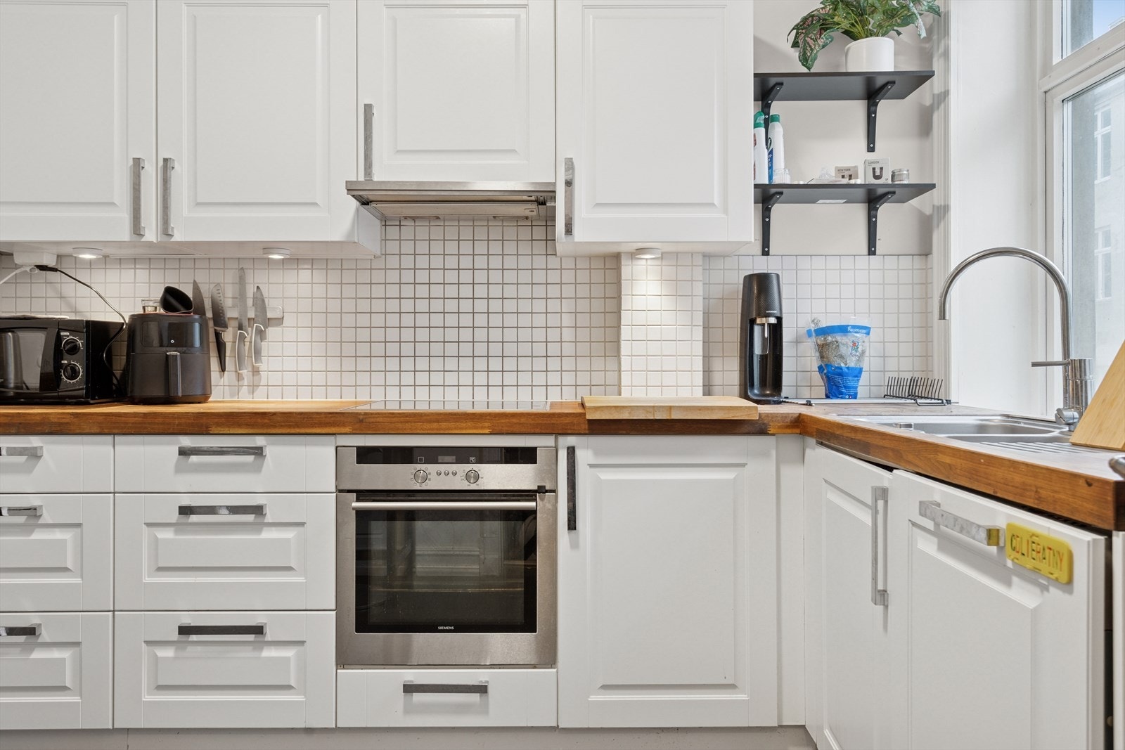 Hvite fronter og integrert stekeovn gir en ryddig arbeidsflate på kjøkkenet. Galleribilde