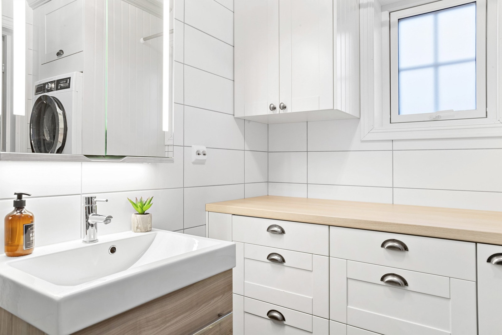 Badet i 1. etasje har varmekabler, veggmontert toalett med innbygget sisterne og servantskap fra Linn Bad Galleribilde