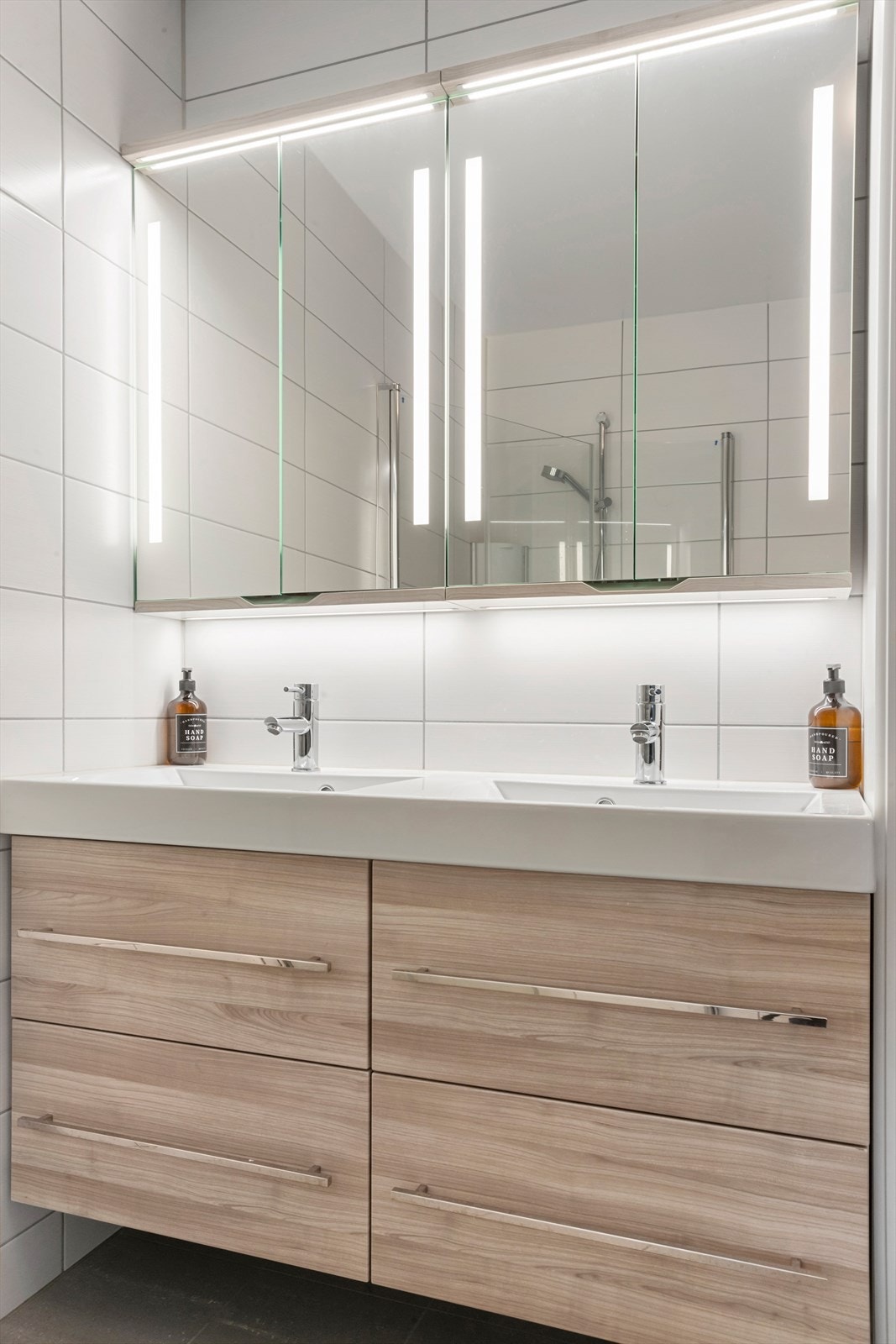 Badet har veggmontert toalett med innbygget sisterne og servantskap med dobbel servant fra Linn Bad Galleribilde