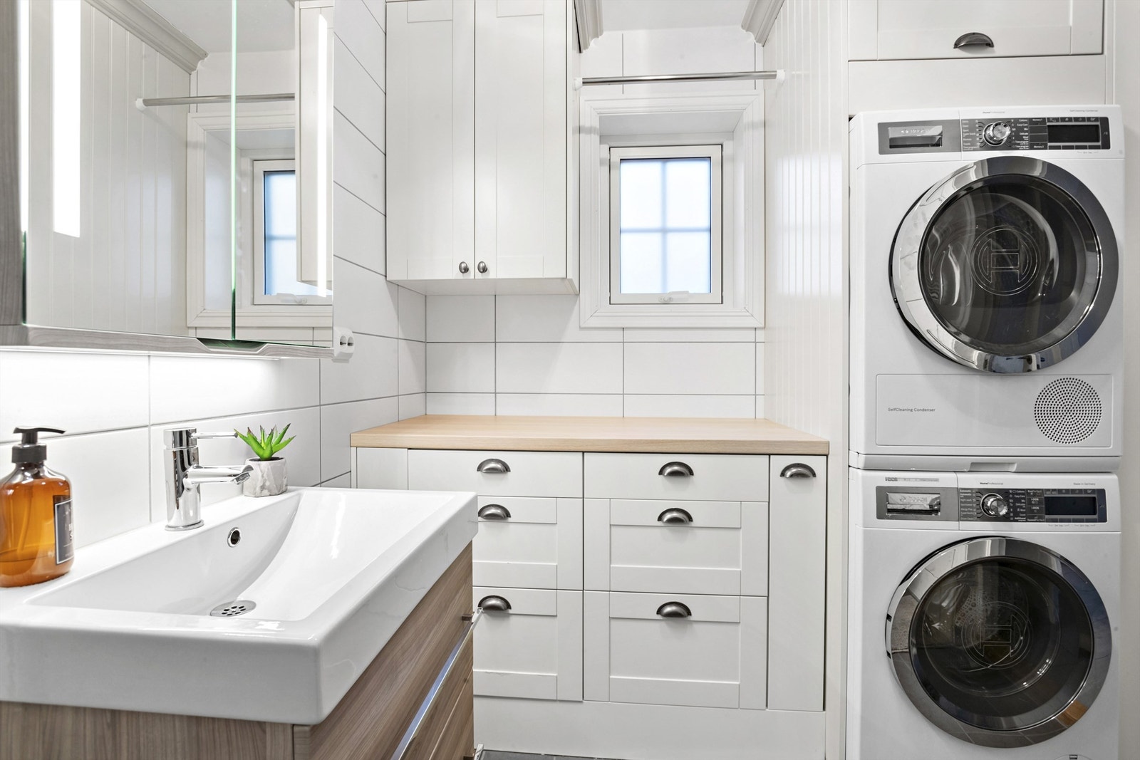 Badet har egendesignet skap- og skuffeløsning i tilknytning til vaskemaskin og tørketrommel Galleribilde