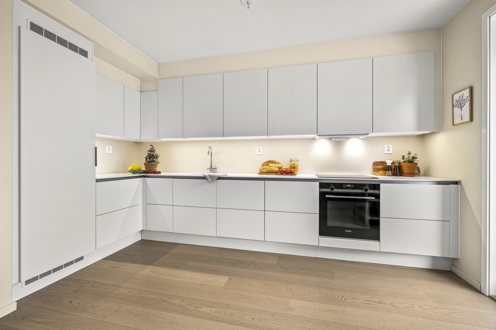 Stilren innredning med glatte, hvite fronter og en solid benkeplate i Corian kompositt. Galleribilde