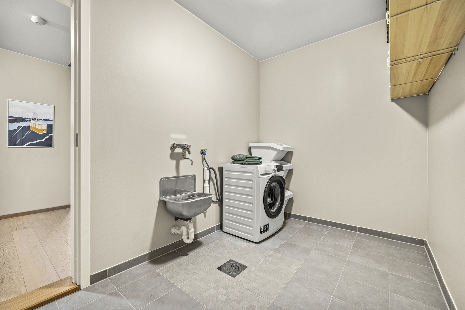 Praktisk, separat vaskerom med flislagt gulv, opplegg for vaskemaskin, utslagsvask og gode oppbevaringsmuligheter. Galleribilde