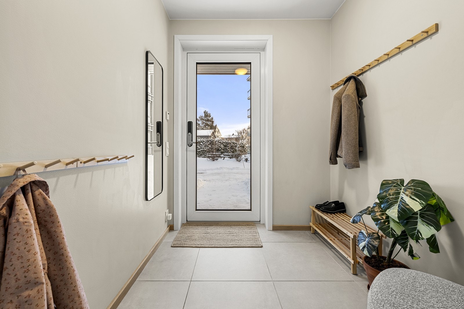 Hyggelig og praktisk inngangsparti med flislagt gulv og lyse, malte overflater - perfekt for yttertøy og sko. Galleribilde