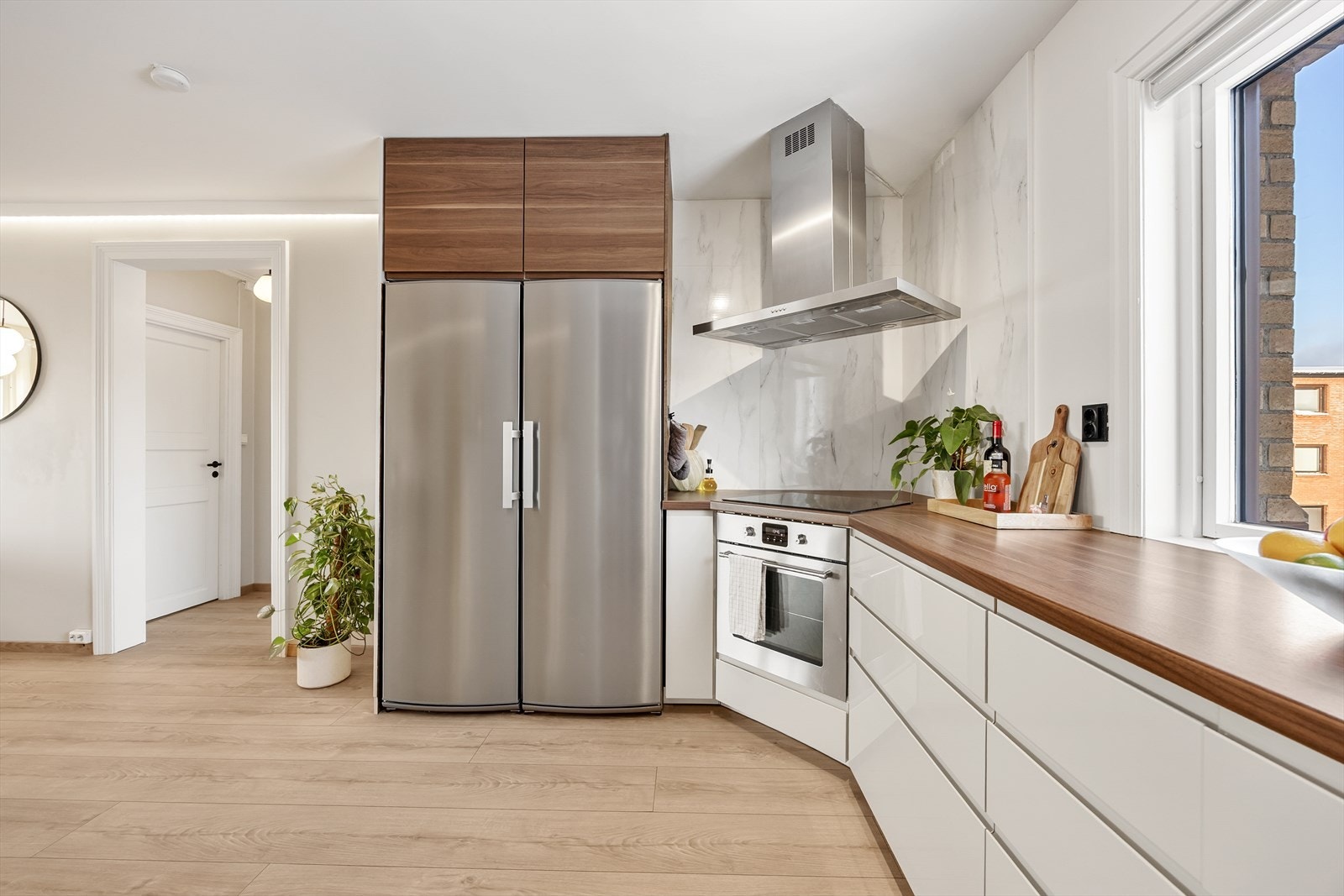 Kjøkkeninnredningen har glatte, hvite fronter og et side-by-side kjøleskap med god kapasitet. Galleribilde