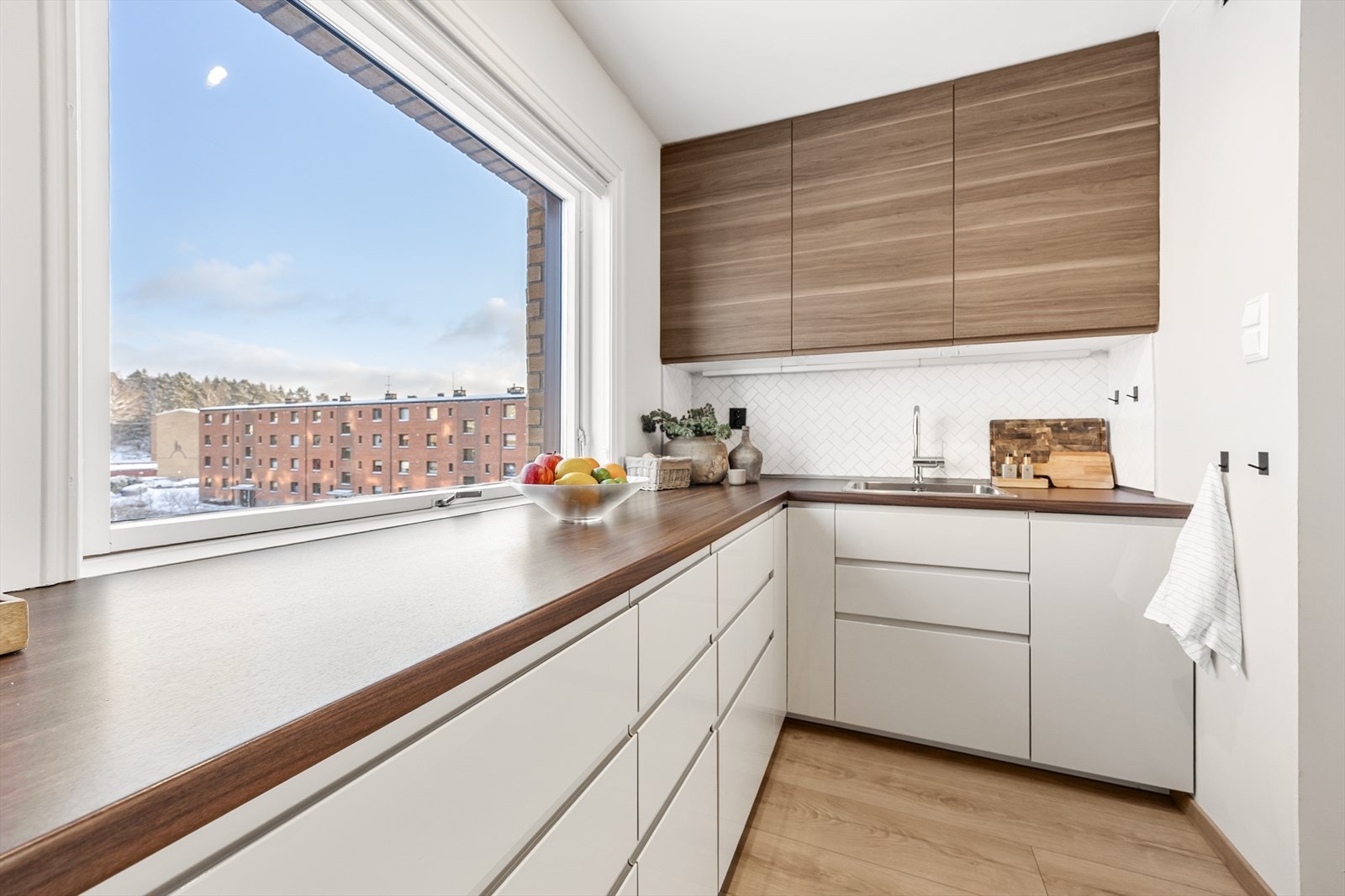 En bred benkeplate i laminat gir rikelig med arbeidsplass foran et stort vindu. Galleribilde