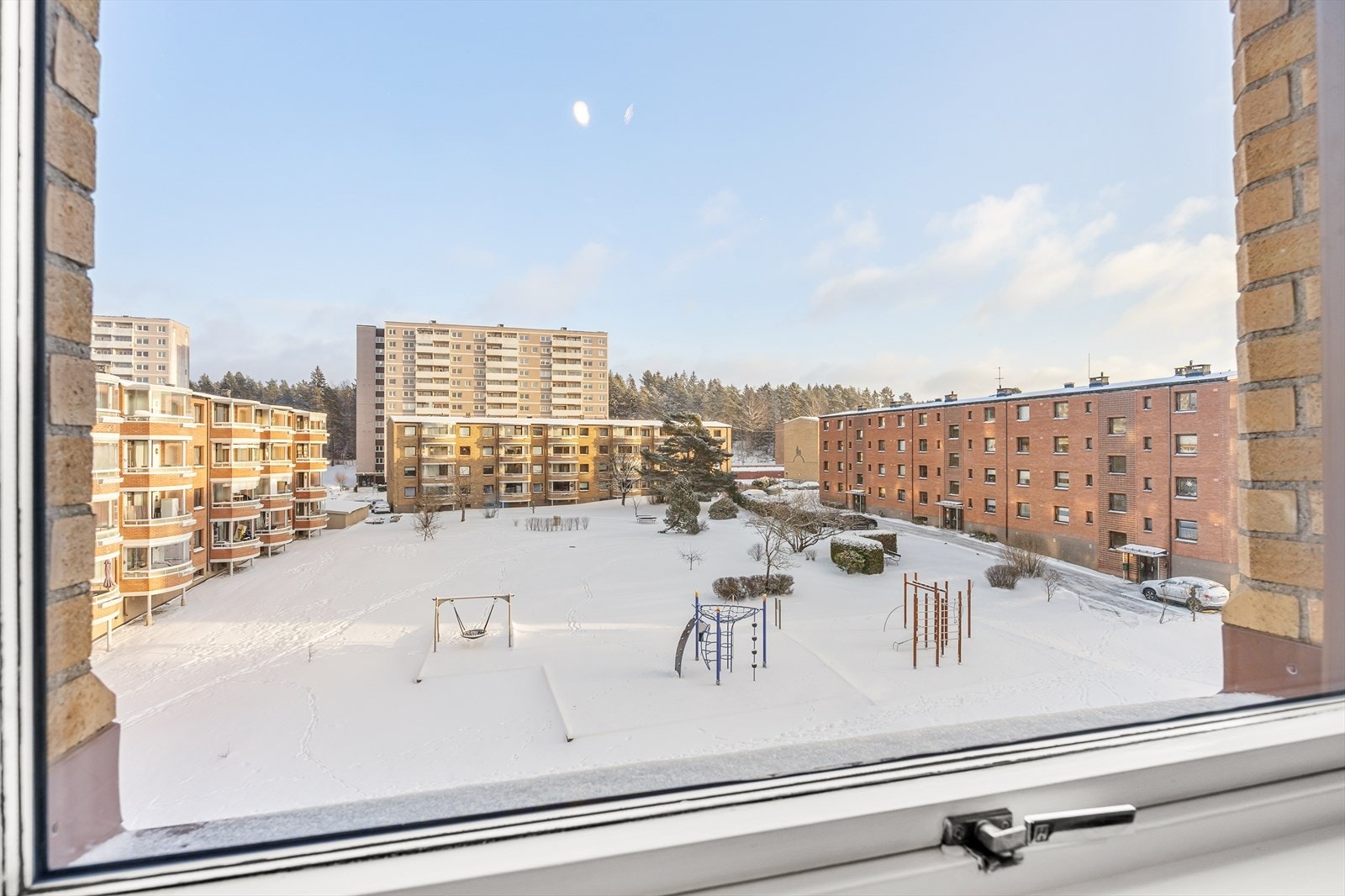 Utsikt mot borettslagets grønne og snødekte fellesarealer. Her kan man følge med på barna som leker rett utenfor. Galleribilde
