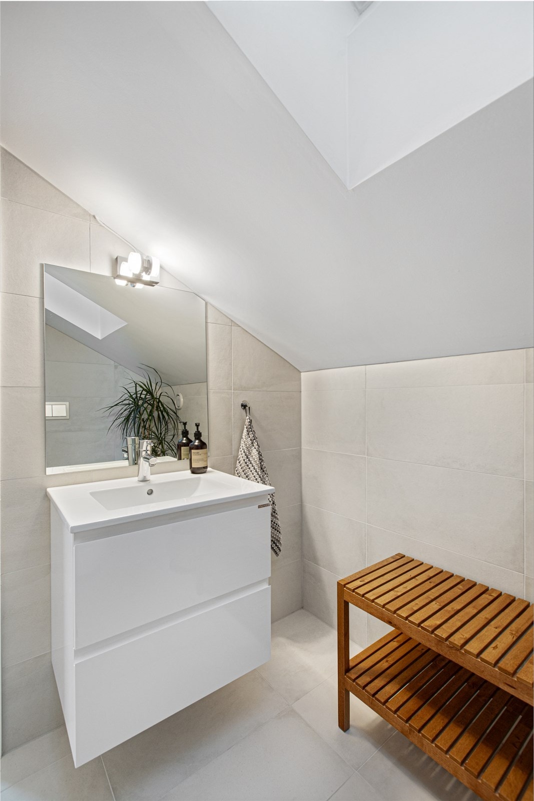 Et stilrent baderom med dusjnisje og innfellbare glassdører, vegghengt toalett og servantinnredning, samt komfortable varmekabler i gulvet. Galleribilde