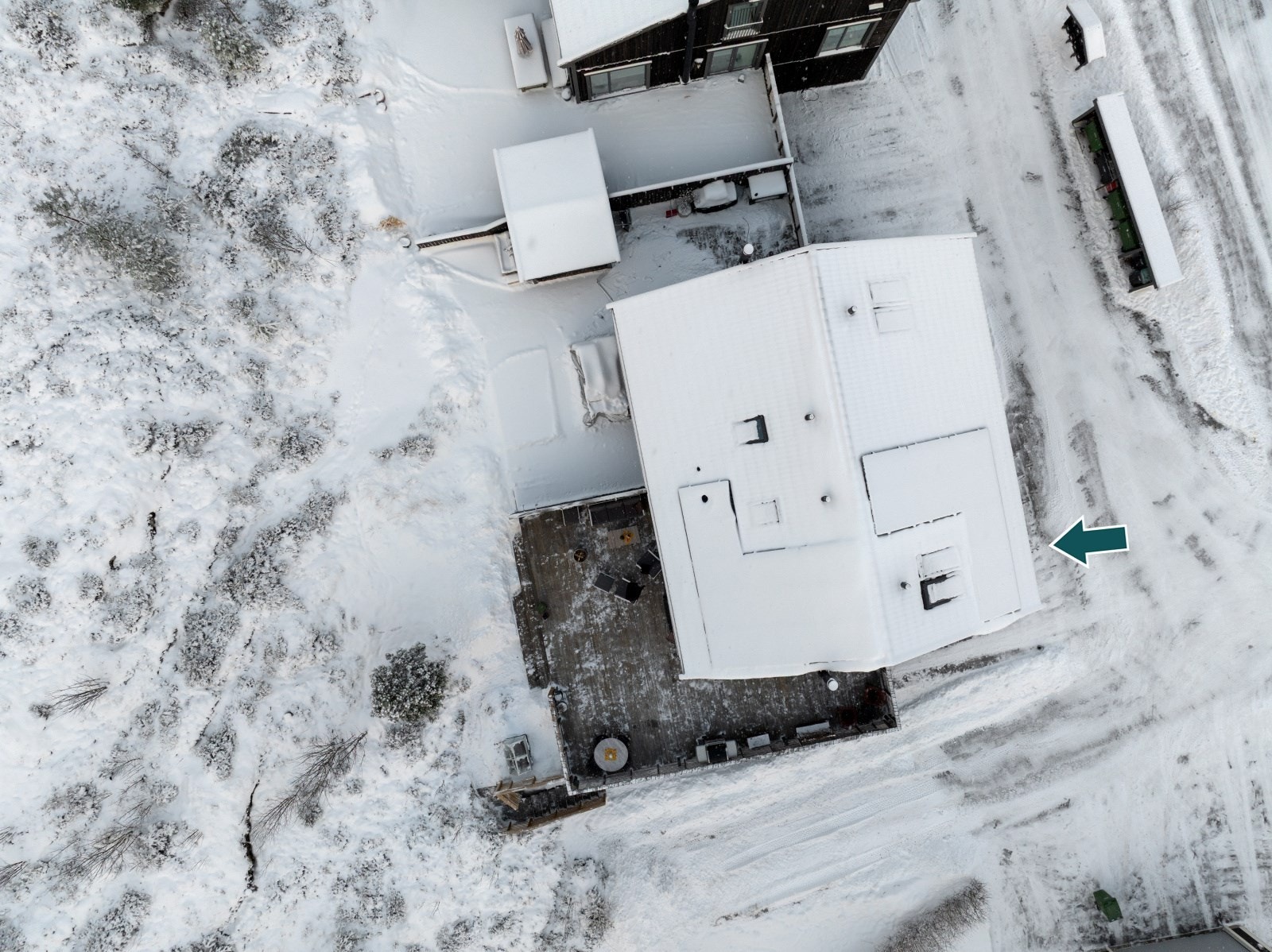 Eiendommen er utstyrt med solceller, som her kan skimtes under snøen på taket. I tillegg ser du den praktiske tretrappen som leder ned fra terrassen til carport og innkjørsel. Galleribilde